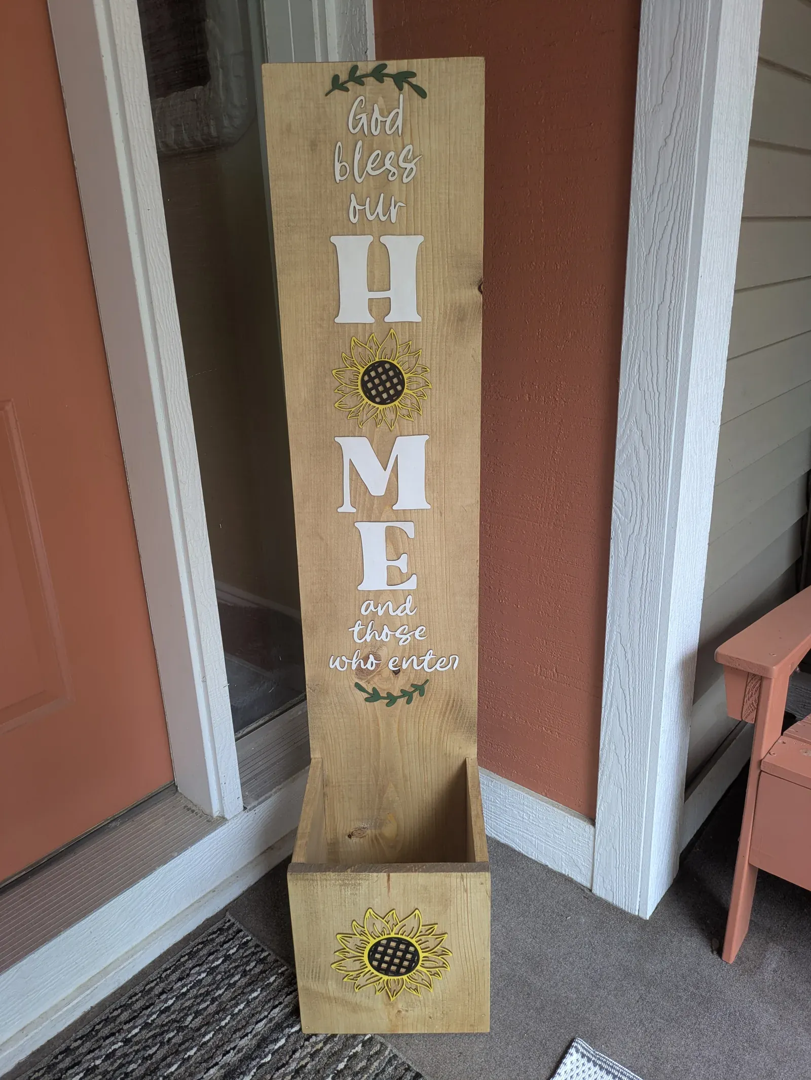 The same decorative sunflower planter post shown from farther back, giving a full view of the post and its planter box on the porch.