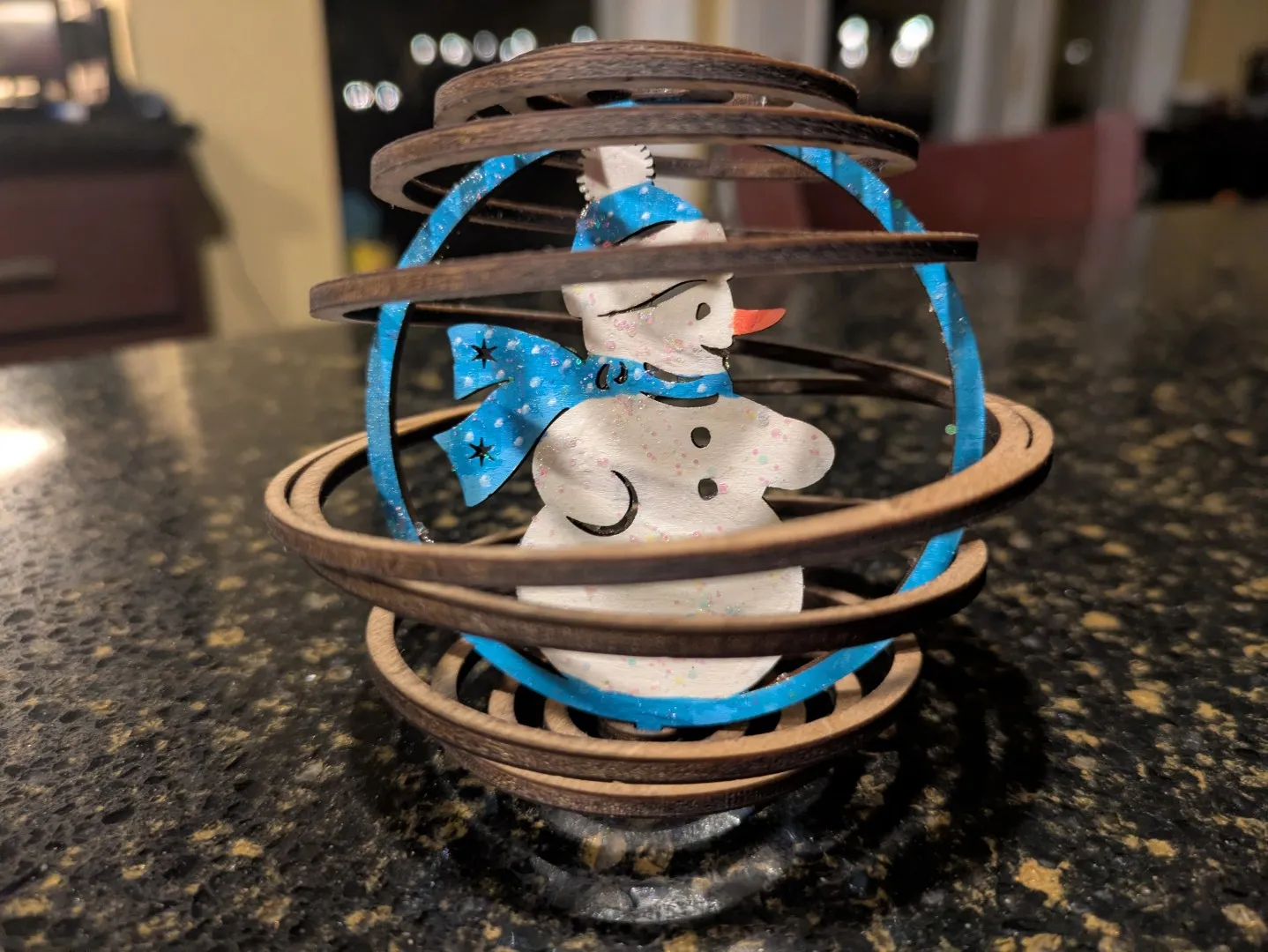 A wooden ornament consisting of a 3D spiral structure. In the middle is a snowman.